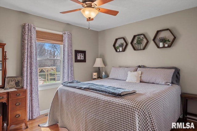 bedroom featuring light wood-style flooring, baseboards, and ceiling fan