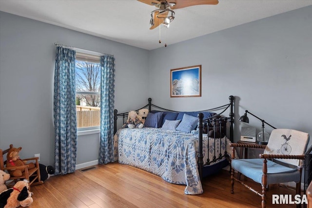 bedroom featuring visible vents, ceiling fan, baseboards, and wood finished floors