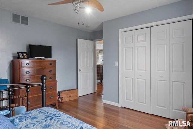 bedroom with visible vents, baseboards, ceiling fan, wood finished floors, and a closet