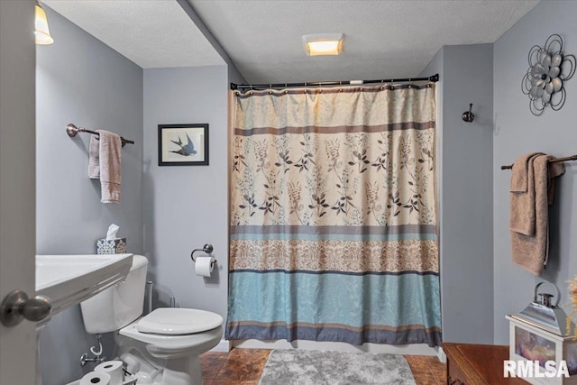 bathroom with a textured ceiling, toilet, and a shower with shower curtain