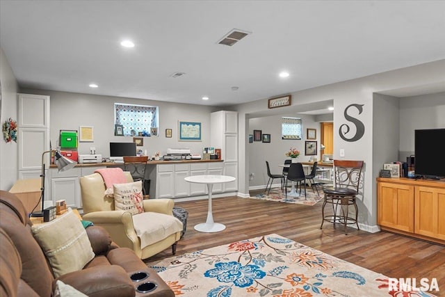 living area with recessed lighting, visible vents, baseboards, and wood finished floors