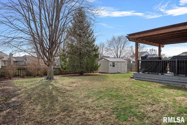 view of yard featuring an outbuilding, a storage unit, a deck, and fence