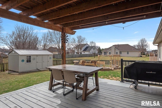 wooden deck featuring fence, outdoor dining area, an outdoor structure, a storage shed, and a lawn