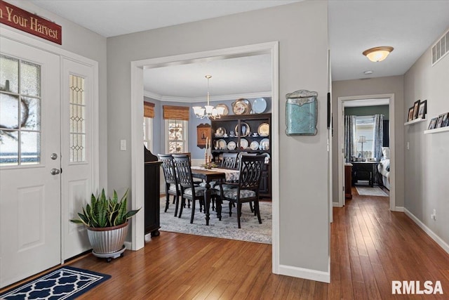 entrance foyer with a chandelier, baseboards, and hardwood / wood-style flooring