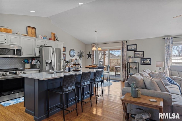 kitchen featuring a kitchen breakfast bar, open floor plan, white cabinetry, stainless steel appliances, and light countertops