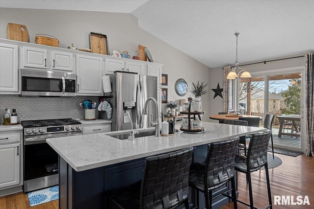 kitchen with a sink, vaulted ceiling, white cabinets, and stainless steel appliances