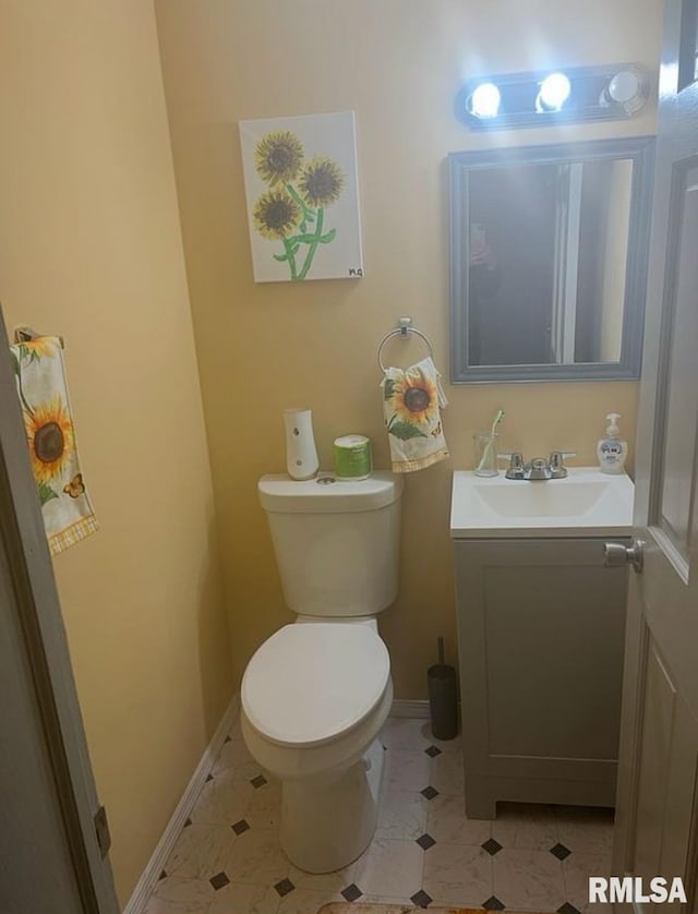 half bath featuring toilet, vanity, and baseboards