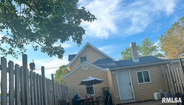 rear view of property featuring a patio and fence