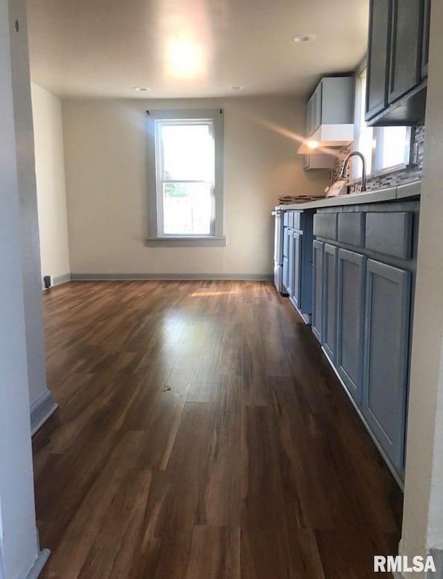 kitchen featuring baseboards, dark wood finished floors, open floor plan, gray cabinets, and a sink