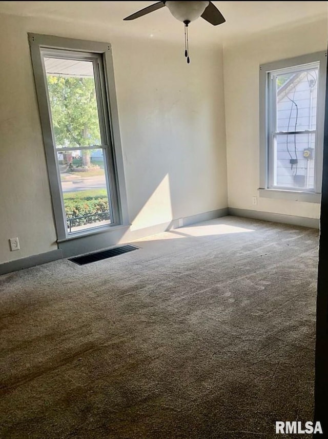 unfurnished room with carpet flooring, visible vents, and a ceiling fan