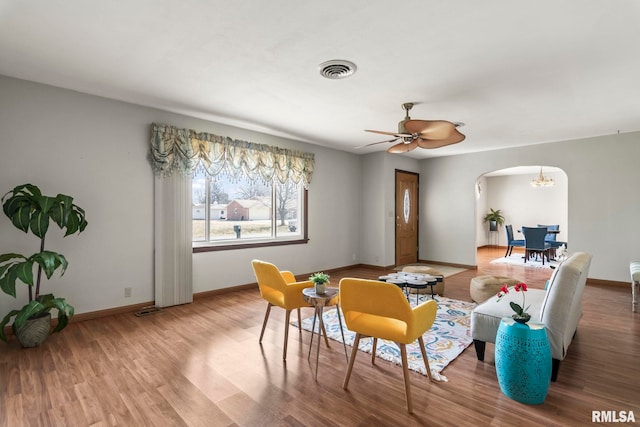 interior space featuring visible vents, ceiling fan, baseboards, wood finished floors, and arched walkways