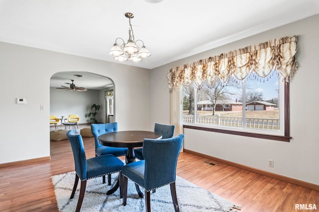 dining room with arched walkways, baseboards, and wood finished floors