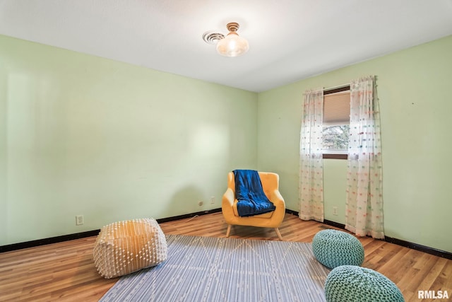 sitting room with baseboards and wood finished floors