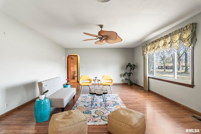 sitting room with a ceiling fan, wood finished floors, visible vents, and baseboards