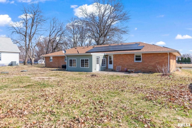 rear view of property featuring solar panels, a yard, crawl space, a patio area, and brick siding