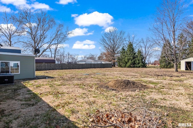 view of yard featuring fence and central AC