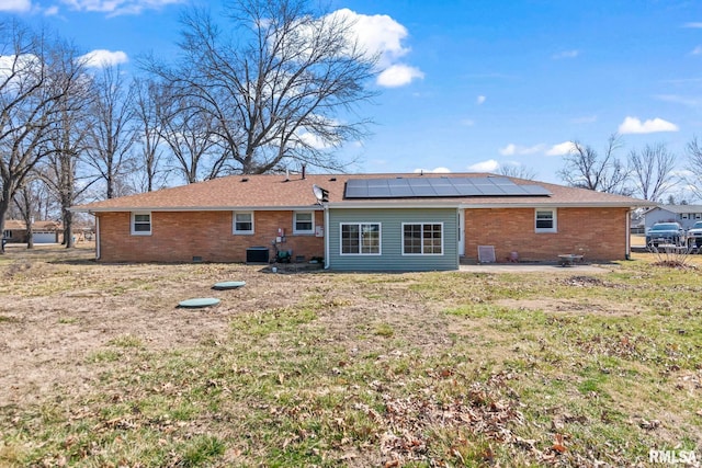 rear view of house featuring a patio, cooling unit, crawl space, brick siding, and solar panels