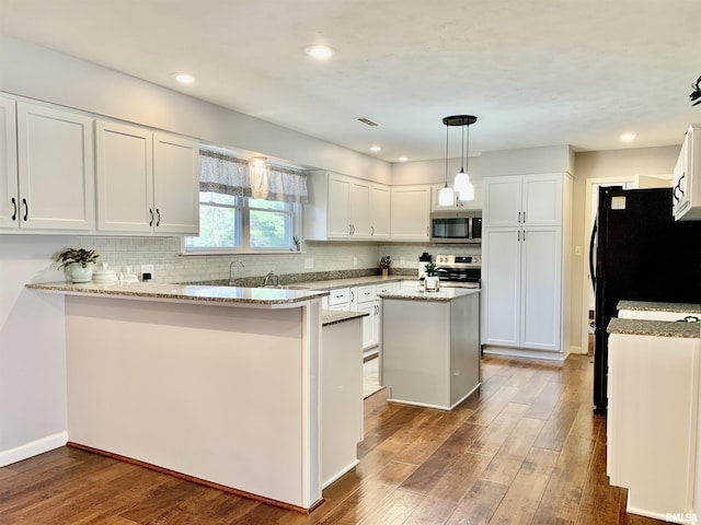 kitchen with wood finished floors, a peninsula, stainless steel appliances, white cabinets, and tasteful backsplash