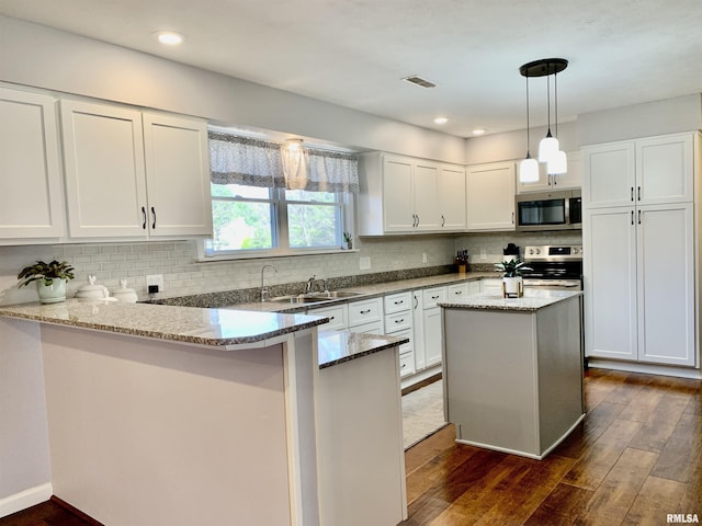 kitchen featuring a sink, a peninsula, white cabinets, and stainless steel appliances