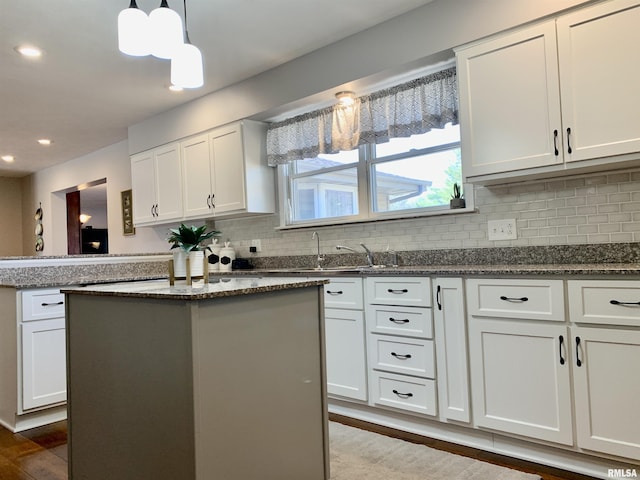 kitchen featuring backsplash, a center island, white cabinetry, dark stone counters, and dark wood-style flooring