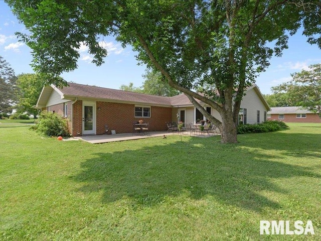 back of property featuring a patio area, a lawn, and brick siding