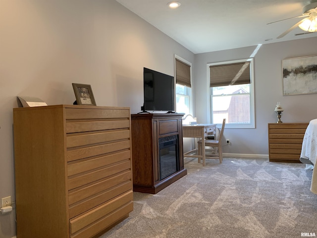 bedroom featuring a ceiling fan, baseboards, recessed lighting, a glass covered fireplace, and light colored carpet