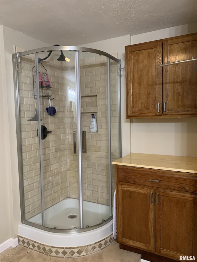 bathroom with a shower stall and a textured ceiling