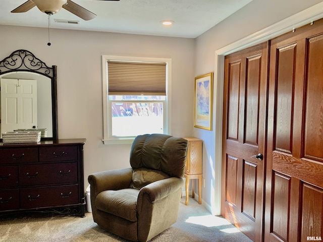 sitting room with light colored carpet, visible vents, and ceiling fan