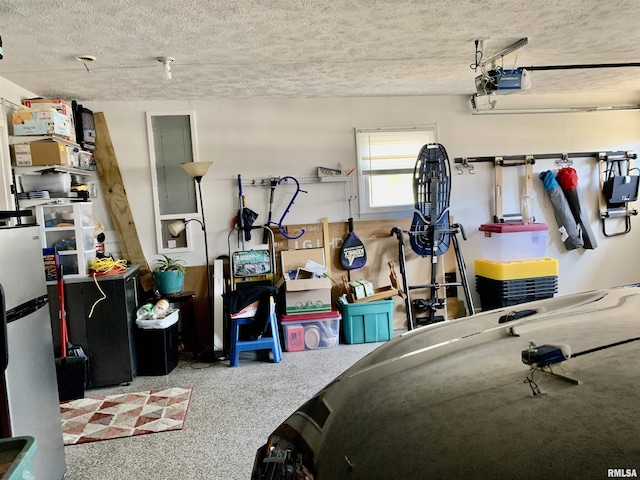 garage with electric panel, a garage door opener, and freestanding refrigerator