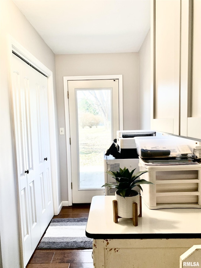 doorway with dark wood finished floors and baseboards