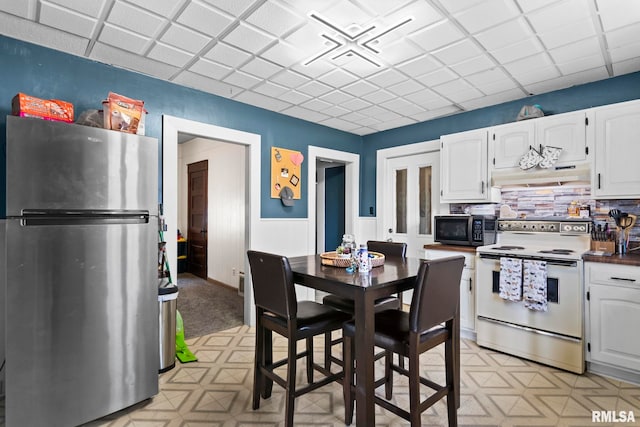 kitchen featuring white range with electric cooktop, white cabinets, freestanding refrigerator, and light floors