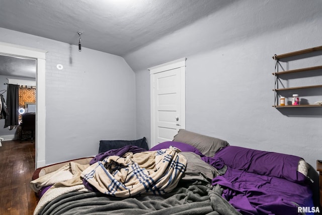 bedroom featuring wood-type flooring, a textured ceiling, and vaulted ceiling