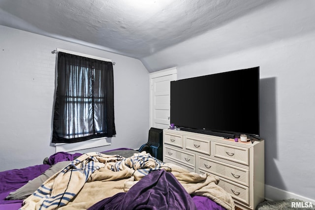 bedroom with a textured ceiling and vaulted ceiling