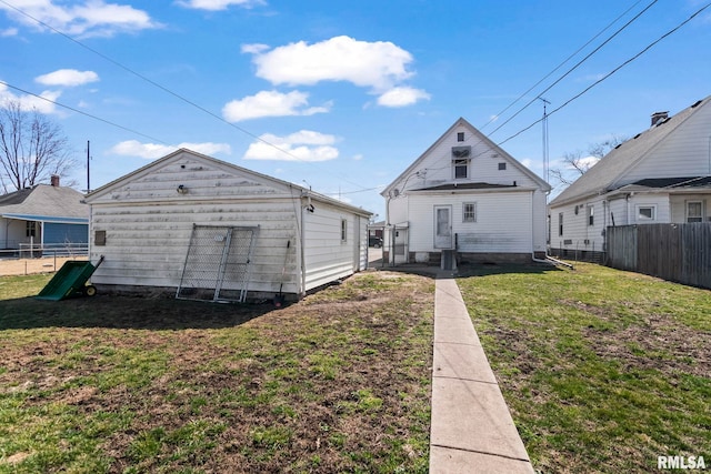 rear view of property with fence and a lawn