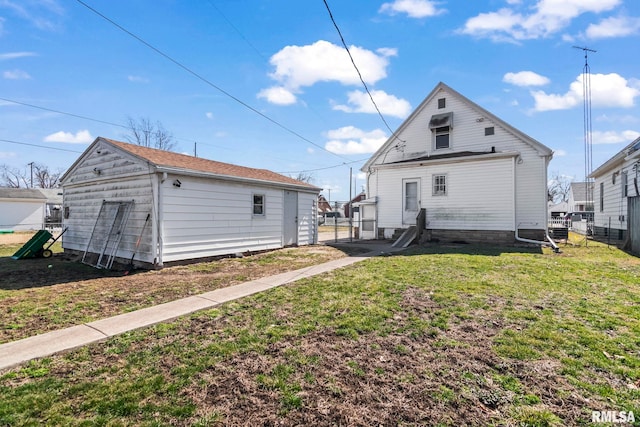 rear view of property featuring an outdoor structure, fence, and a lawn