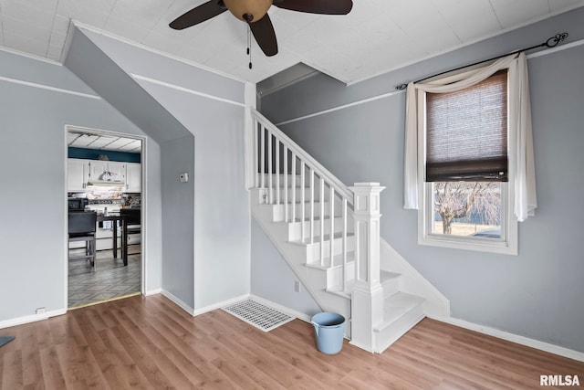 stairs featuring baseboards, wood finished floors, visible vents, and ceiling fan