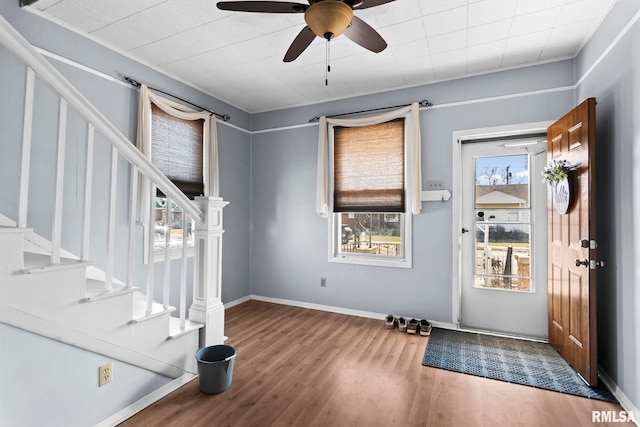 foyer with ceiling fan, stairway, and wood finished floors