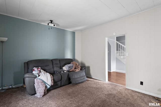 carpeted living area featuring crown molding, stairway, and baseboards