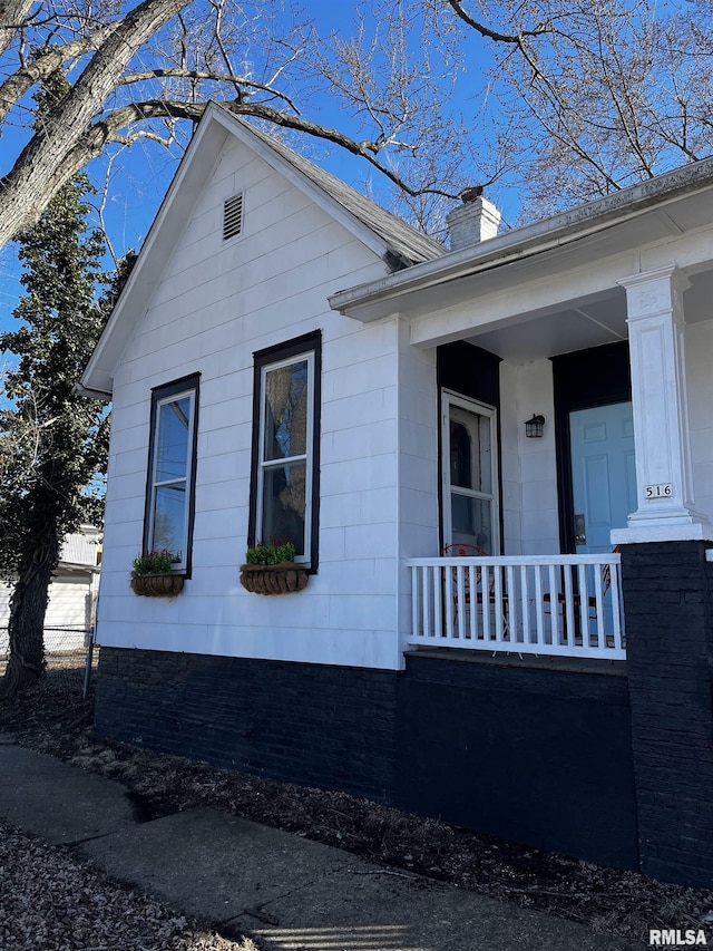 view of side of home featuring covered porch and a chimney