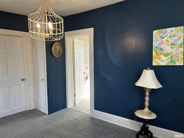 unfurnished room featuring carpet flooring, a notable chandelier, and baseboards