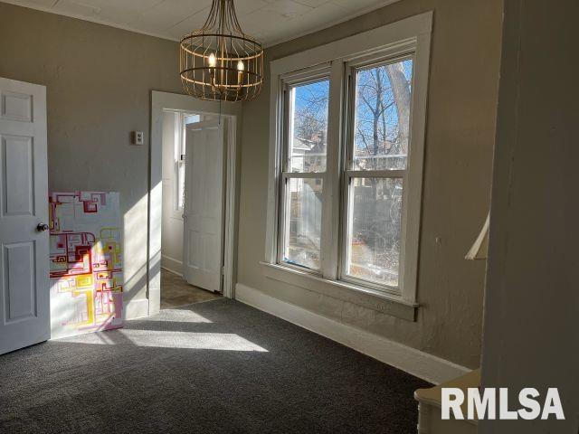 unfurnished dining area featuring baseboards, carpet floors, and an inviting chandelier