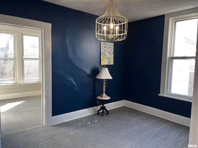 empty room with a notable chandelier, baseboards, and carpet floors