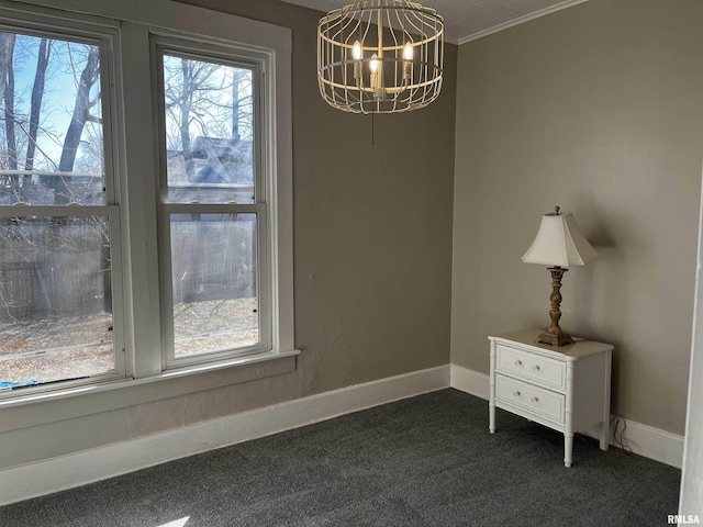 unfurnished dining area featuring a notable chandelier, ornamental molding, baseboards, and dark colored carpet