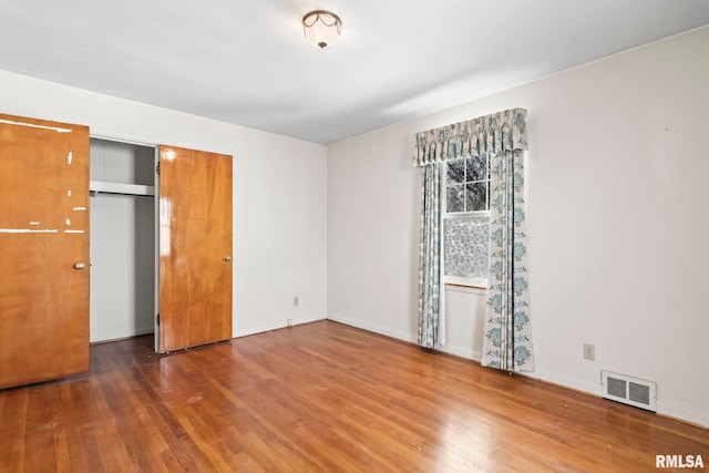 unfurnished bedroom with visible vents, baseboards, and hardwood / wood-style floors