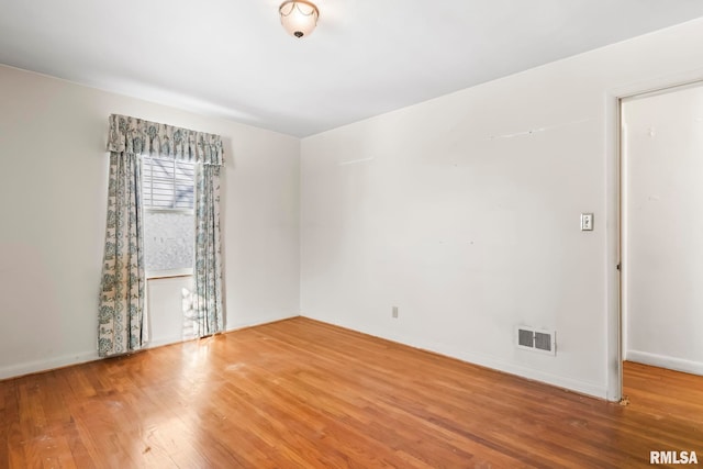 unfurnished room with visible vents, baseboards, and wood finished floors