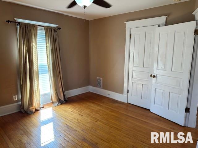 unfurnished bedroom featuring hardwood / wood-style floors, visible vents, and baseboards