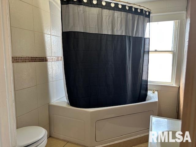 full bath with tile patterned floors, shower / bath combination with curtain, tile walls, and toilet