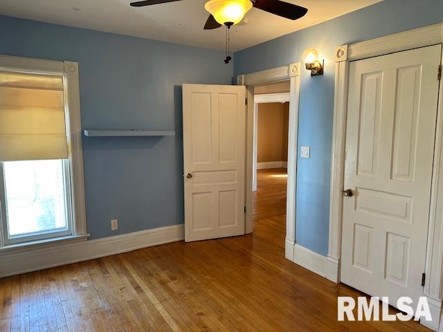 unfurnished bedroom with a ceiling fan, baseboards, and wood finished floors