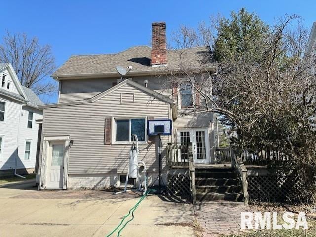 back of property with a wooden deck and a chimney