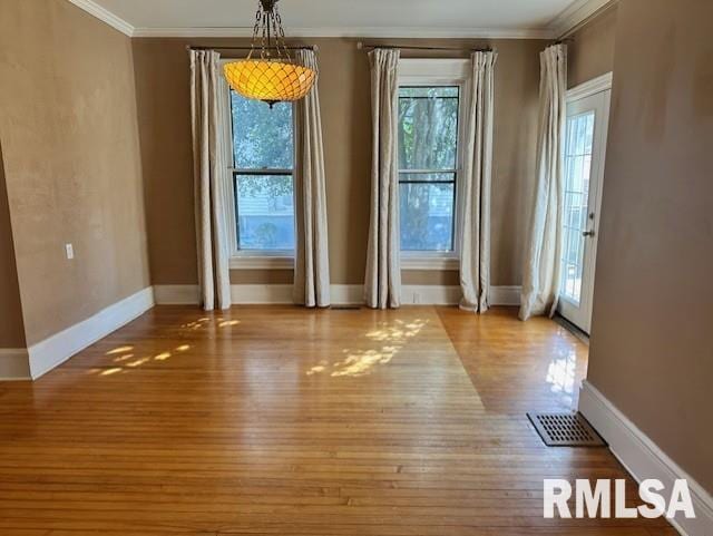 unfurnished dining area featuring wood finished floors, baseboards, and ornamental molding